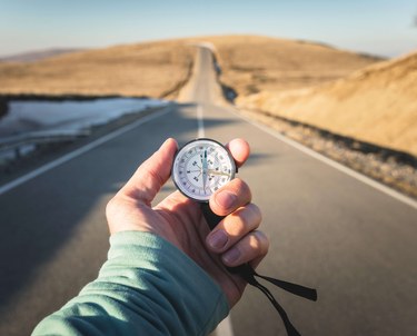 Person Holding Compass With Long Road into Desert